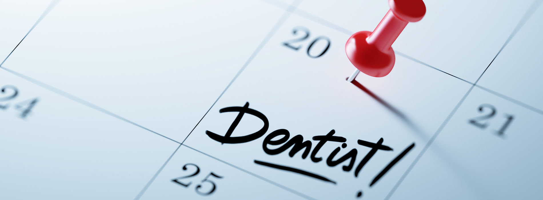 The image shows a calendar with  dentist  written on it under a magnifying glass icon, indicating an appointment or reminder for dental care.