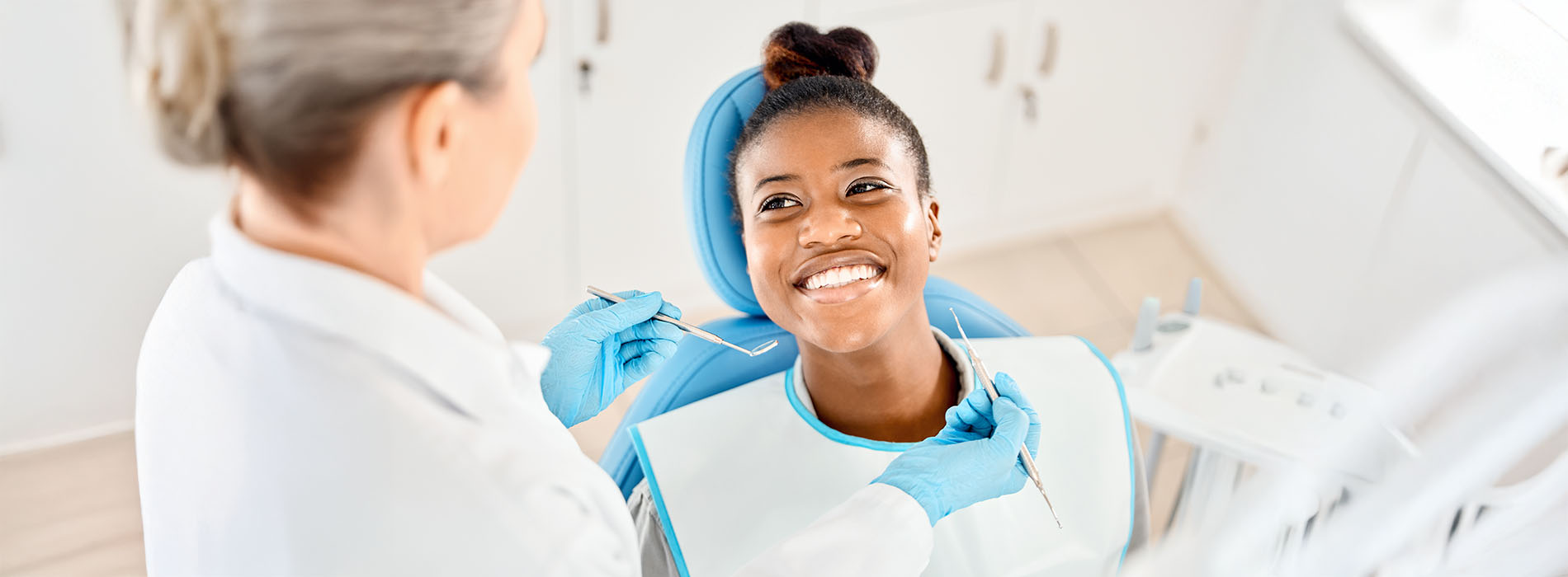 A woman in a dental chair being attended to by a dentist.