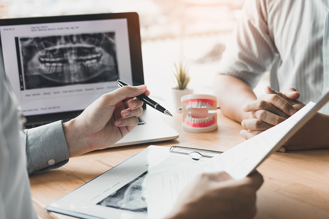 A split-screen photograph showing a dental professional reviewing an X-ray with a patient, who appears to be signing a document while seated at a desk.