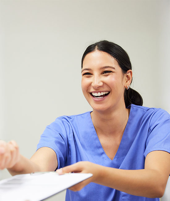 A smiling female nurse handing a document to a patient.