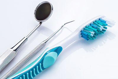 This image features a collection of dental tools including a pair of scissors and toothbrushes with blue bristles, placed on a white background.