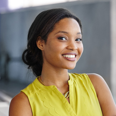 A woman with a radiant smile poses confidently against a modern backdrop.