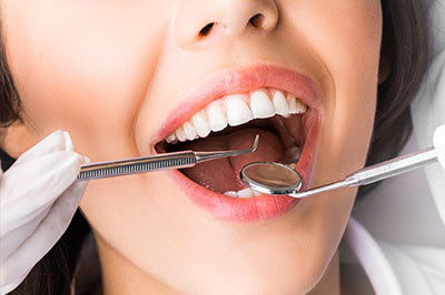 Alt text  A woman with a wide smile sitting in a dental chair while undergoing dental treatment.