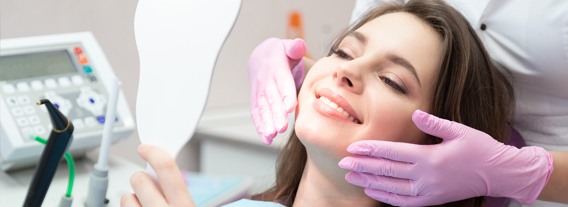 The image depicts a woman lying down with her eyes closed, receiving dental care from a professional wearing a white coat and a purple surgical mask.