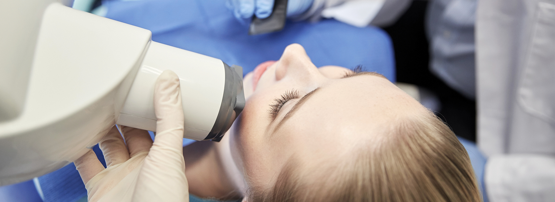 A person receiving dental care with a dentist using an instrument to examine their mouth.