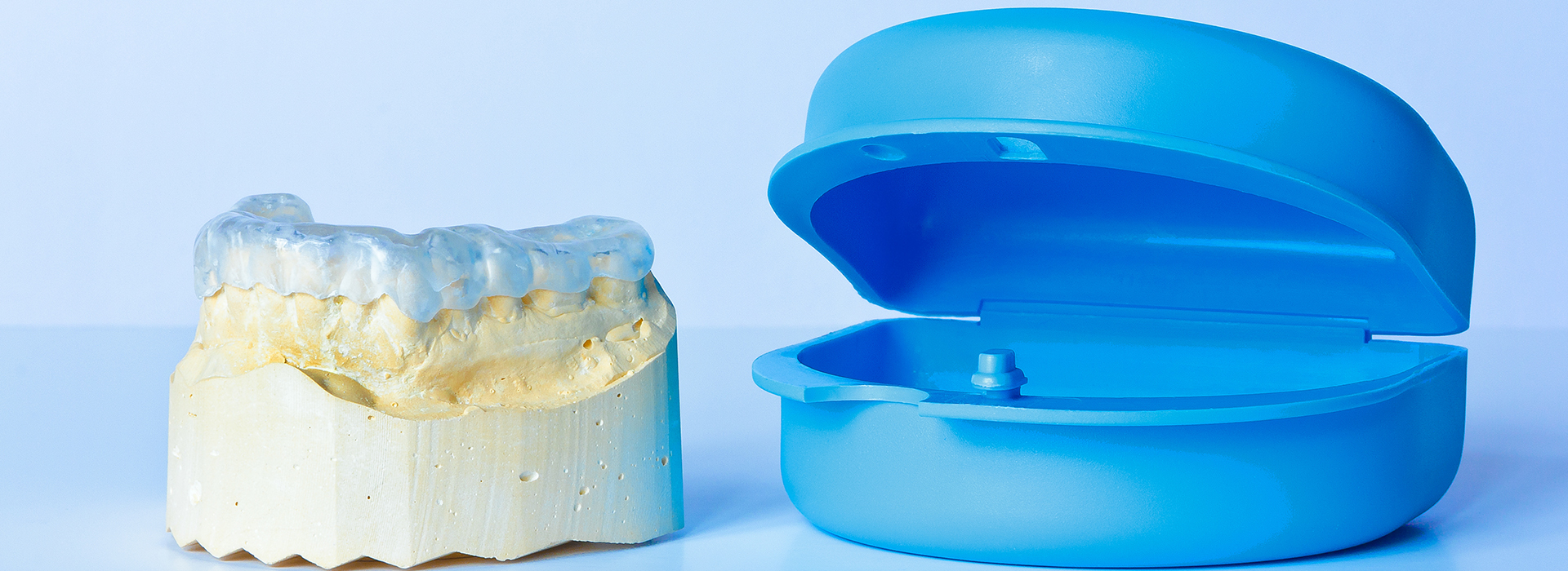 A photograph comparing two different types of dental implants  one with an abutment and the other without, placed side by side against a blue background.