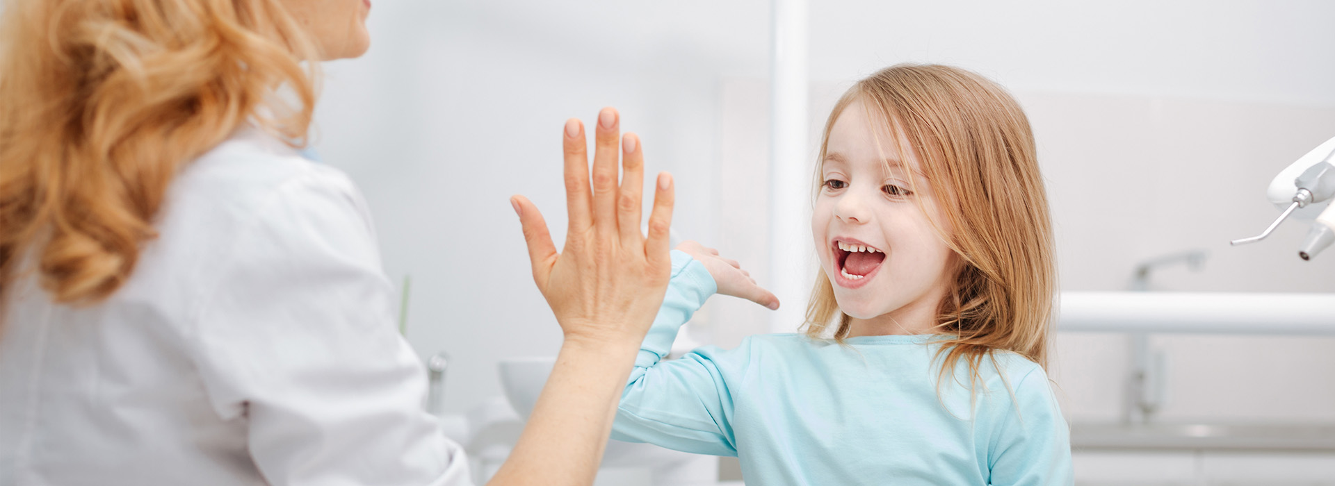 The image shows a woman and a young girl in a bathroom setting, with the woman reaching out towards the child who appears to be reacting with surprise or excitement.