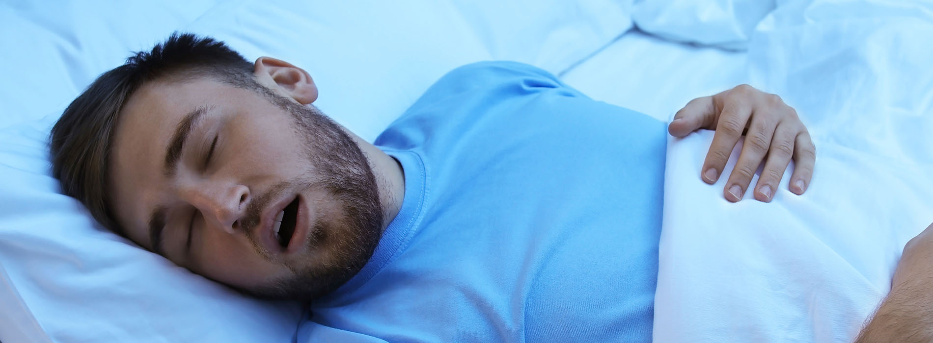 A man lying down in bed with his eyes closed.