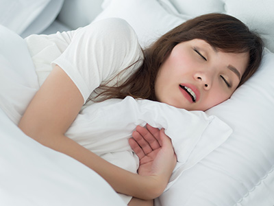 A woman asleep in bed with her mouth open.